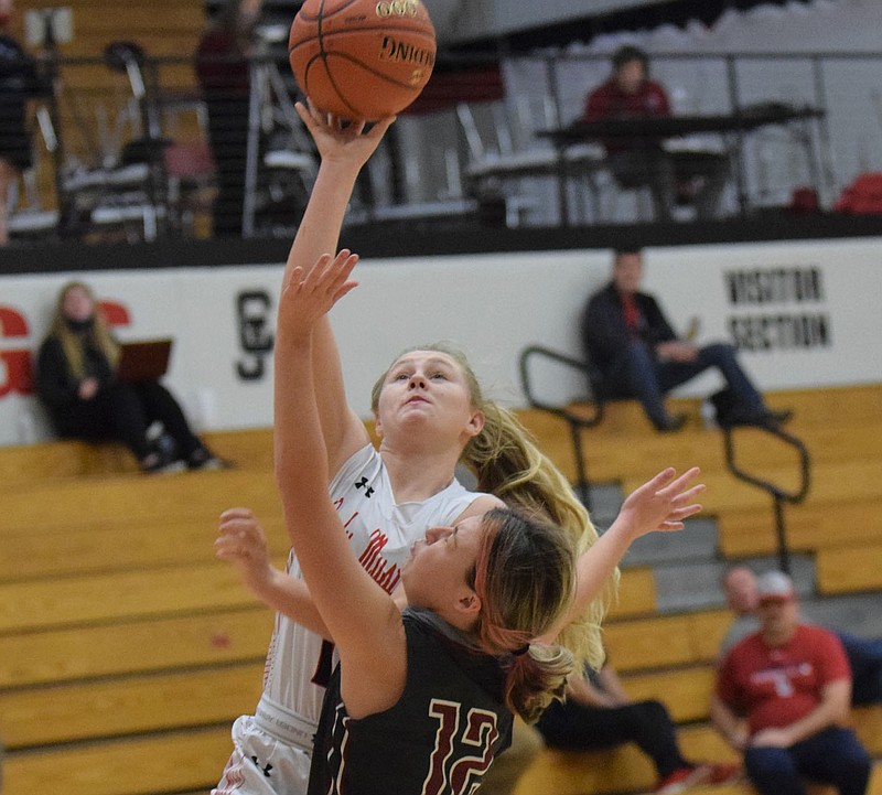 RICK PECK/SPECIAL TO MCDONALD COUNTY PRESS McDonald County's Carlee Cooper goes in for a layup while Nevada's Grace Barnes defends during the Lady Mustangs' 39-33 OT win on Dec. 3 in the CJ Classic High School Girls Basketball Tournament.