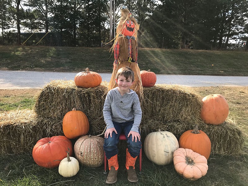 Courtesy Photo Bronc Divine takes a break from the pumpkin patch to pose by a scarecrow and several pumpkins. Divine enjoyed a non-traditional field trip at Rocky Comfort Elementary, along with several of his classmates.