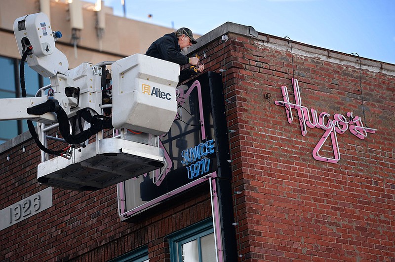 Lew Indorf, a longtime technician with Ken's Signs in Fayetteville, reassembles the neon sign above iconic Fayetteville restaurant Hugo's Wednesday, Dec. 9, 2020, after making repairs from atop a bucket truck on Block Avenue. Indorf installed a new segment of neon and repaired a broken wire to make the sign work properly again. Visit nwaonline.com/201210Daily/ for today's photo gallery. 
(NWA Democrat-Gazette/Andy Shupe)