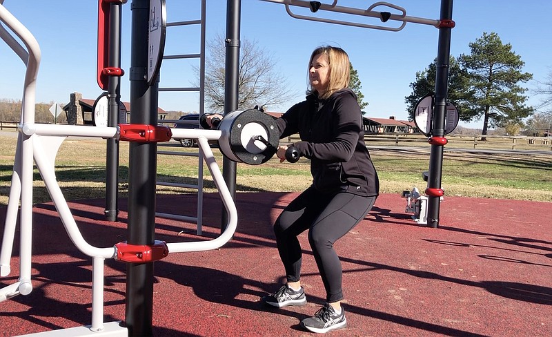 Hannah Pinkston demonstrates the Squatting Arm Ergometer exercise at the AARP FitLot in Murray Park for Master Class. (Arkansas Democrat-Gazette/Celia Storeyy