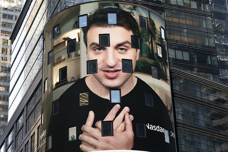 Brian Chesky, CEO of Airbnb, is shown on an electronic screen at the Nasdaq MarketSite, Thursday, Dec. 10, 2020, in New York. The San Francisco-based online vacation rental company holds its IPO Thursday. (AP Photo/Mark Lennihan)