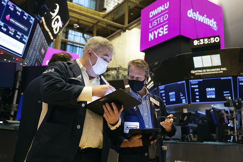 In this photo provided by the New York Stock Exchange, traders Edward McCarthy, left, and Robert Charmak work on the floor during the Delwinds Insurance Acquisition Corp. IPO, Friday Dec. 11, 2020. U.S. stocks fell in morning trading Friday as prospects for another aid package from Washington faded while a surge in virus cases threatens to inflict more damage on an already battered economy. (Colin Ziemer/New York Stock Exchange via AP)