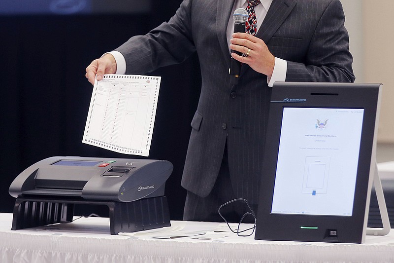FILE - In this Thursday, Aug. 30, 2018 file photo, a Smartmatic representative demonstrates his company's system which has scanners and touch screens with printout options at a meeting of the Secure, Accessible & Fair Elections Commission in Grovetown, Ga. Antonio Mugica, CEO of Smartmatic, the electronic voting company being targeted by allies of Donald Trump, said baseless claims that it helped flip the 2020 election for Joe Biden threatens to undermine Americans’ faith in democracy and the company is threatening legal action unless Fox News, Rudy Giuliani and other Trump allies fully retract baseless claims. (Bob Andres/Atlanta Journal-Constitution via AP, File)