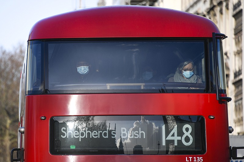 Passengers wear face masks as they sit on a double decker bus, in London, Tuesday, Dec. 15, 2020. London and its surrounding areas will be placed under Britain's highest level of coronavirus restrictions beginning Wednesday as infections rise rapidly in the capital, the health secretary said Monday, adding that a new variant of the virus may be to blame for the spread. (AP Photo/Alberto Pezzali)