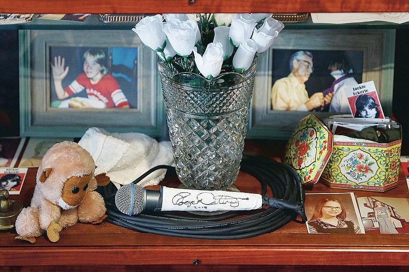 FILE - This Thursday, Nov. 21, 2019, file photo shows a signed microphone by The Who's Roger Daltrey on display in a memorial cabinet at the Finneytown High School secondary campus in Finneytown, Ohio, along with other mementoes of the three Finneytown students killed in a stampede at the band's 1979 Cincinnati concert. Every year, Finneytown alumni hold a memorial scholarship fundraising event to honor their three classmates. In 2020, because of the coronavirus, they organized a show of prerecorded video interviews with The Who's frontman, Roger Daltrey, guitarist-songwriter Pete Townshend and a mix of recorded and live discussions with relatives of the 11 people killed on Dec. 3, 1979. (AP Photo/John Minchillo, File)