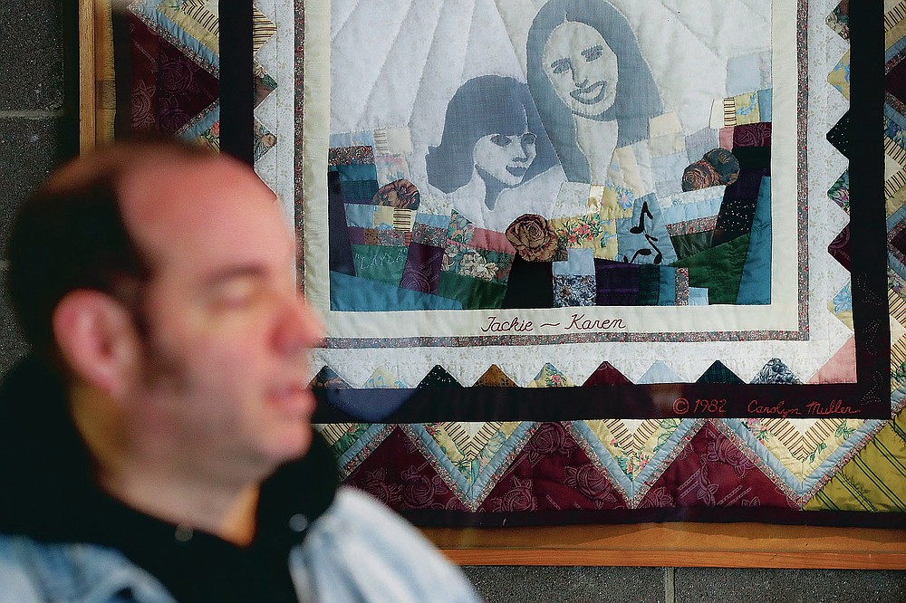 FILE-In this Thursday, Nov. 21, 2019 file photo, Fred Wittenbaum, of the P.E.M. scholarship that memorializes the three Finneytown students killed in a stampede at The Who's Dec. 3, 1979 concert, is interviewed beside a quilted memorial to the dead at the Finneytown High School secondary campus, in Finneytown, Ohio. Every year, Finneytown alumni hold a memorial scholarship fundraising event to honor their three classmates. In 2020, because of the coronavirus, they organized a show of prerecorded video interviews with The Who's frontman, Roger Daltrey, guitarist-songwriter Pete Townshend and a mix of recorded and live discussions with relatives of the 11 people killed on Dec. 3, 1979. (AP Photo/John Minchillo, File)
