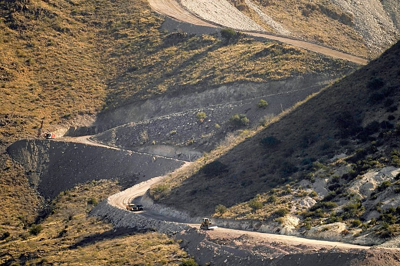 A pathway cleared by explosives to make way for border wall construction separates Mexico, right, and the USA, Wednesday, Dec. 9, 2020, in Guadalupe Canyon, Ariz.  Construction of the border wall, mostly in government owned wildlife refuges and Indigenous territory, has led to environmental damage and the scarring of unique desert and mountain landscapes that conservationists fear could be irreversible. (AP Photo/Matt York)