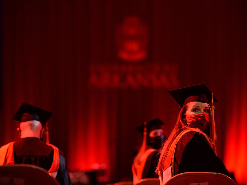 JaLynn Heckadon (right) of Nevada, Mo., looks for family members in the crowd Thursday as she prepares to graduate with a master of science in operations  management from the University of Arkansas at Bud Walton Arena. Go to nwaonline.com/201218Daily/ for today's photo gallery. 
(NWA Democrat-Gazette/Andy Shupe)