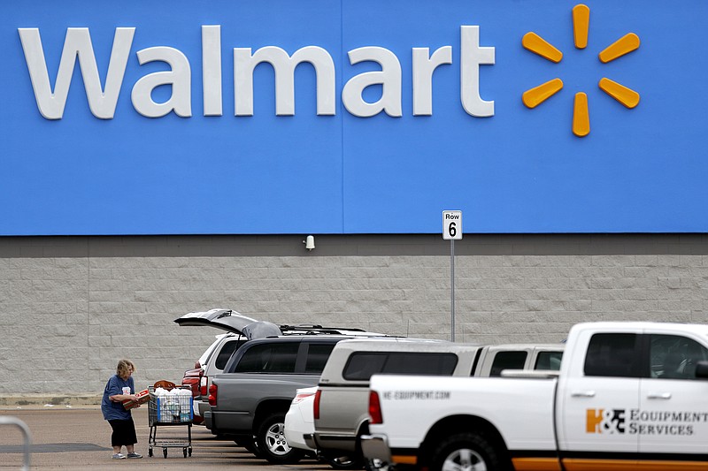 FILE - In this March 31, 2020 file photo, a woman pulls groceries from a cart to her vehicle outside of a Walmart store in Pearl, Miss. Walmart is teaming with the General Motors' Cruise autonomous vehicle unit to test automated package delivery in Arizona. (AP Photo/Julio Cortez, File)