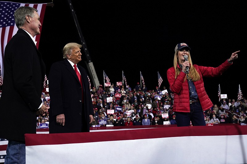 FILE - In this Dec. 5, 2020, file photo Sen. Kelly Loeffler, R-Ga., speaks as President Donald Trump and Sen. David Perdue, R-Ga., listen at a campaign rally at Valdosta Regional Airport, Saturday, Dec. 5, 2020, in Valdosta, Ga. Many Republican voters in Georgia are angry; certain that widespread voter fraud — claims of which are baseless — cost President Donald Trump the election. Most Republican voters in the state interviewed said they were prepared to put their skepticism aside to vote for Perdue and Loeffler in their races against Democrats Jon Ossoff and Raphael Warnock. (AP Photo/Evan Vucci, File)