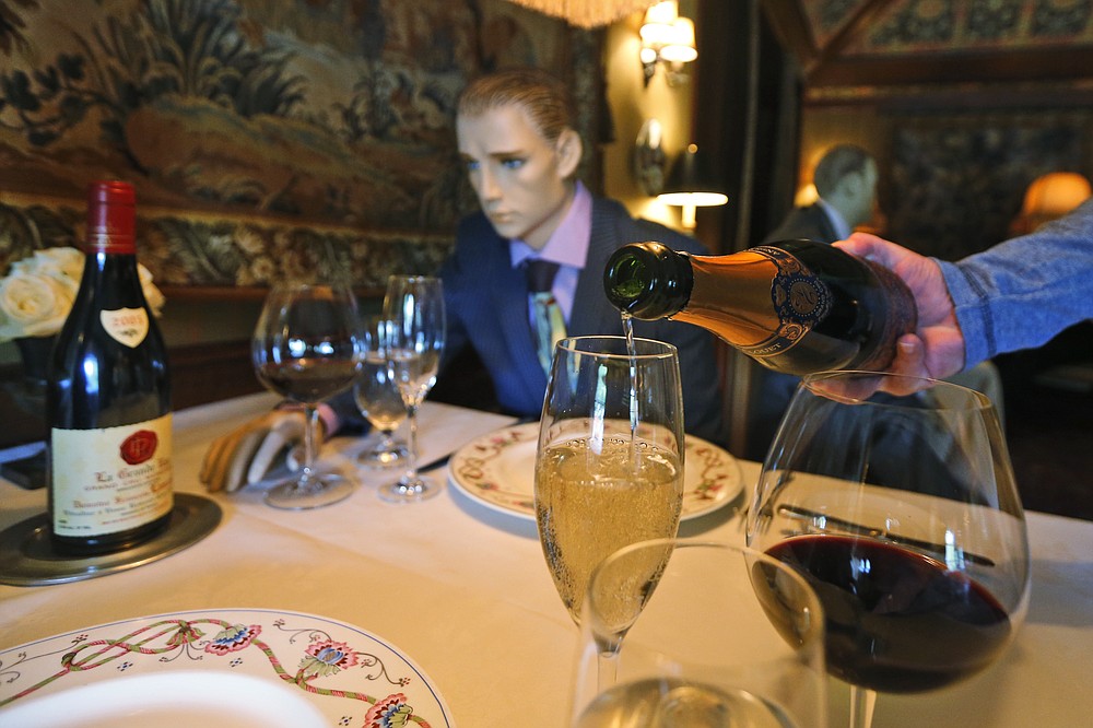 FILE - In this May 14, 2020, file photo Champagne is poured at a table where mannequins will provide social distancing at the Inn at Little Washington as they prepare to reopen their restaurant in Washington, Va. Stuffed into the new emergency relief package is a morsel that President Donald Trump has long had on the buffet of his economic wish list: restoring full tax breaks for restaurant business meals. (AP Photo/Steve Helber, File)