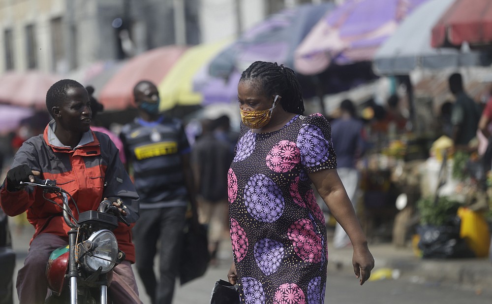 A woman wearing a face mask to protect against coronavirus, walks at a market in Lagos, Nigeria, Thursday Dec. 24, 2020. Africa’s top public health official says another new variant of the coronavirus appears to have emerged in Nigeria, but further investigation is needed. The discovery could add to new alarm in the pandemic after similar variants were announced in recent days in Britain and South Africa and sparked the swift return of travel restrictions. (AP Photo/Sunday Alamba)