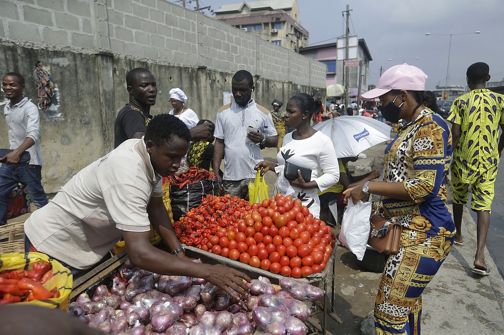People buy vegetables, at a market in Lagos, Nigeria, Thursday Dec. 24, 2020. Africa’s top public health official says another new variant of the coronavirus appears to have emerged in Nigeria, but further investigation is needed. The discovery could add to new alarm in the pandemic after similar variants were announced in recent days in Britain and South Africa and sparked the swift return of travel restrictions. (AP Photo/Sunday Alamba)