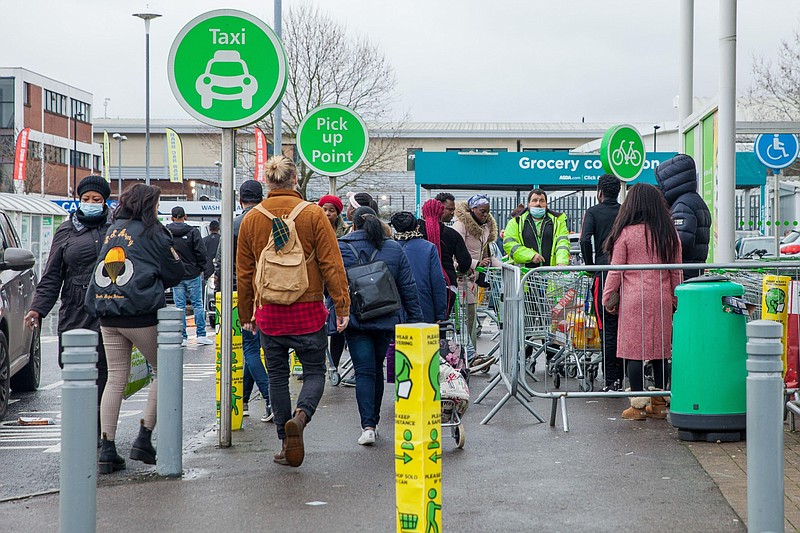 Customers stand in front of the collection area outside an Asda supermarket store in London on Dec. 21, 2020. MUST CREDIT: Bloomberg photo by Betty Laura Zapata.