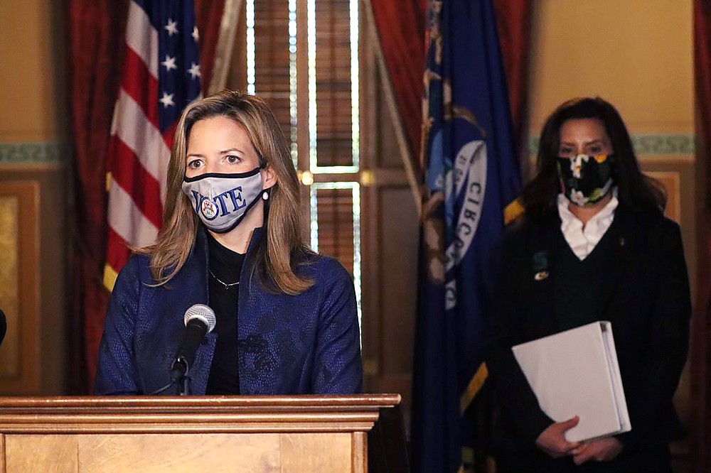 FILE - In this Wednesday, Oct. 28, 2020 photo provided by the Michigan Office of the Governor, Michigan Secretary of State Jocelyn Benson addresses the state in Lansing, Mich., accompanied by Gov. Gretchen Whitmer, background. “Just like we have seen a lot of legislators making ill-advised decisions to hold hearings that ended up being more political theater than policy debates, we can similarly expect legislators to further this hyper-partisan agenda to restrict the vote,” says Benson, a Democrat. (Michigan Office of the Governor via AP)
