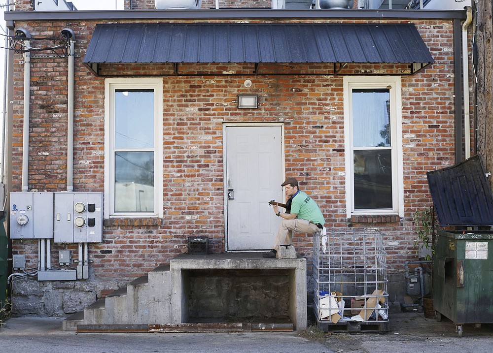 Ty Yell plays guitar, Thursday, December 10, 2020 at an alleyway between First and Second Streets from Elm to Chestnut Streets in downtown Rogers. These alleyways will be part of an upcoming alleyway revitalization project that will be part of the city's cultural plan. The idea is to relocate dumpsters and resurface the alleyway, add lighting and amenities with artwork so that the alleyways become a comfortable place for pedestrians. Check out nwaonline.com/201211Daily/ for today's photo gallery.
(NWA Democrat-Gazette/Charlie Kaijo)