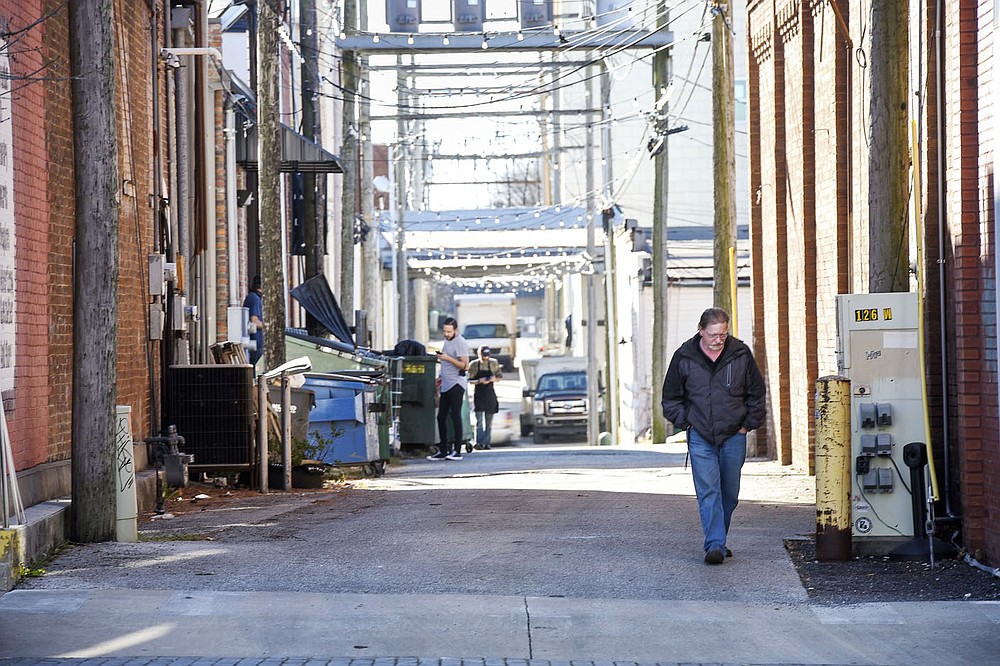 A bystander walks by, Thursday, December 10, 2020 at an alleyway between First and Second Streets from Elm to Chestnut Streets in downtown Rogers. These alleyways will be part of an upcoming alleyway revitalization project that will be part of the city's cultural plan. The idea is to relocate dumpsters and resurface the alleyway, add lighting and amenities with artwork so that the alleyways become a comfortable place for pedestrians. Check out nwaonline.com/201211Daily/ for today's photo gallery. 
(NWA Democrat-Gazette/Charlie Kaijo)