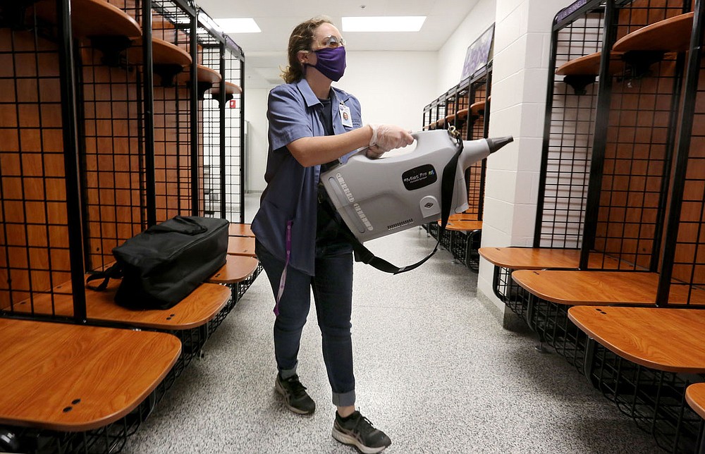 Hannah Huckabee, a custodian with Fayetteville Public Schools, uses a hospital-grade mister Dec. 15 to disinfect the Fayetteville High School volleyball team locker room. The cleaning procedure takes place after hours when no students are in the area. Check out nwaonline.com/201228Daily/ and nwadg.com/photos for a photo gallery.
(NWA Democrat-Gazette/David Gottschalk)