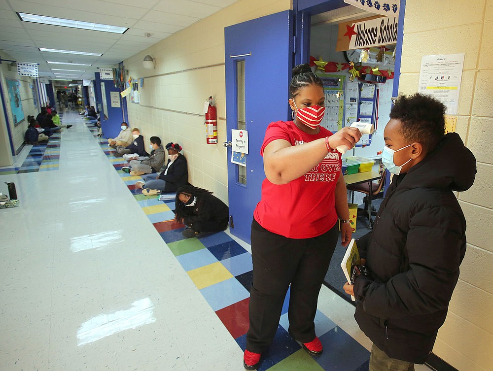 Fourth-grade teacher Cher Fields takes the temperature of Kendrick Hudler Dec. 11 as he enters the building for the school day at Terry Elementary School in Little Rock. 
Check out nwaonline.com/201228Daily/ and nwadg.com/photos for a photo gallery.
(Arkansas Democrat-Gazette/Thomas Metthe)