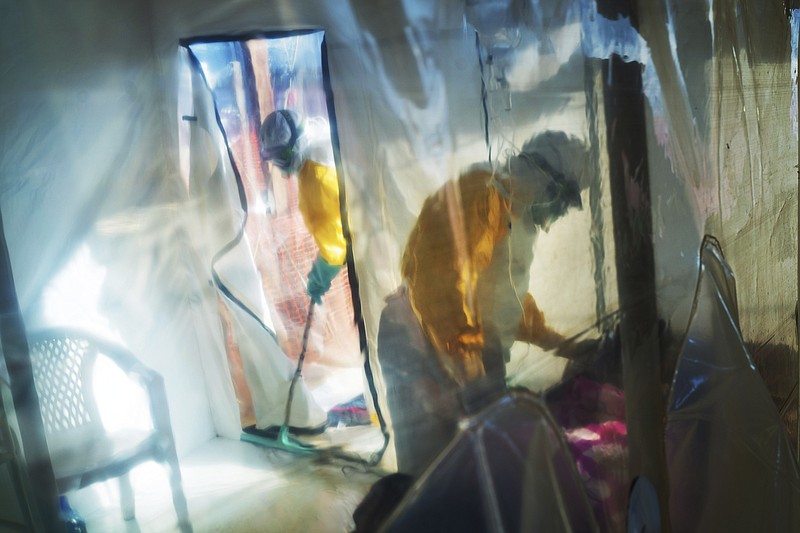 FILE - In this July 13, 2019, file photo, health workers wearing protective suits tend to an Ebola victim kept in an isolation tent in Beni, Democratic Republic of Congo. The task of vaccinating millions of people in poor and developing countries against COVID-19 faces monumental obstacles, and it's not just a problem of affording and obtaining doses. Rumors flew about the Ebola vaccines, including the idea they were meant to kill people, said Dr. Maurice Kakule, an Ebola survivor who worked in vaccination campaigns. Similar suspicions are spreading about the COVID-19 vaccine, he said. (AP Photo/Jerome Delay, File)