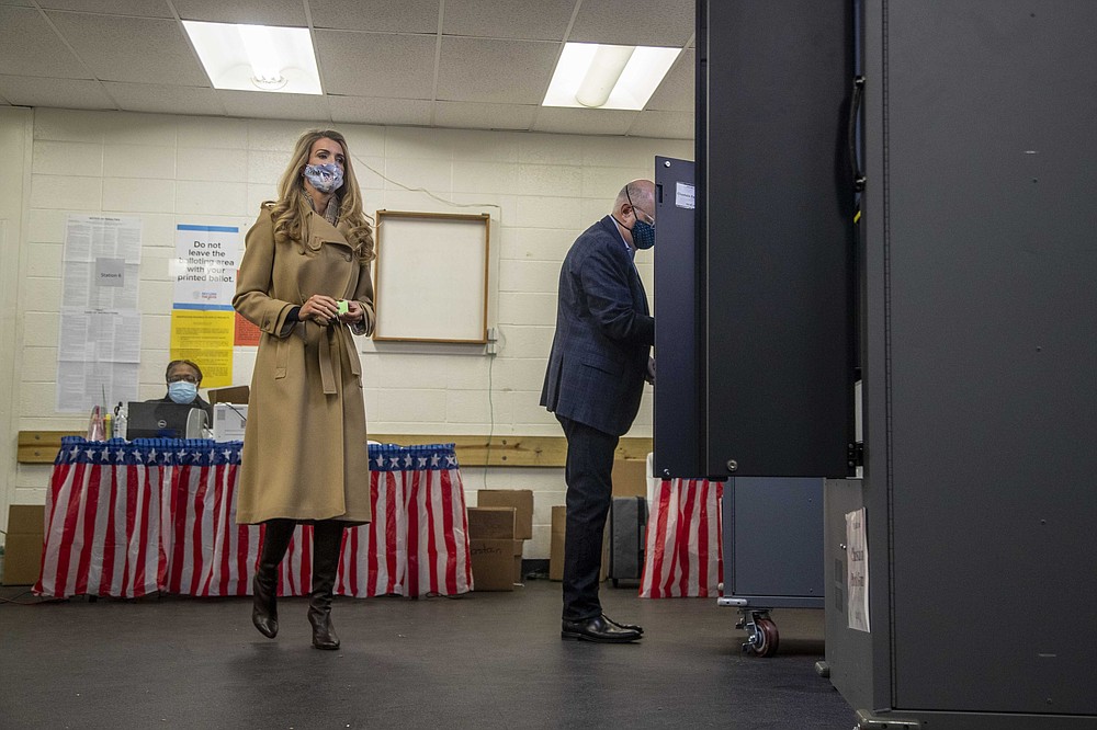 U.S. Sen. Kelly Loeffler, R-Ga., prepares to cast her ballot alongside her husband, Jeff Sprecher, right, during early voting in runoff elections at Chastain Park Gymnasium in Atlanta's Chastain Park neighborhood, Wednesday, Dec. 16, 2020. Democratic candidates Jon Ossoff and the Rev. Raphael Warnock are trying to to unseat Republican Sens. David Perdue and Kelly Loeffler in the runoff elections that will determine which party controls the Senate. (Alyssa Pointer/Atlanta Journal-Constitution via AP)