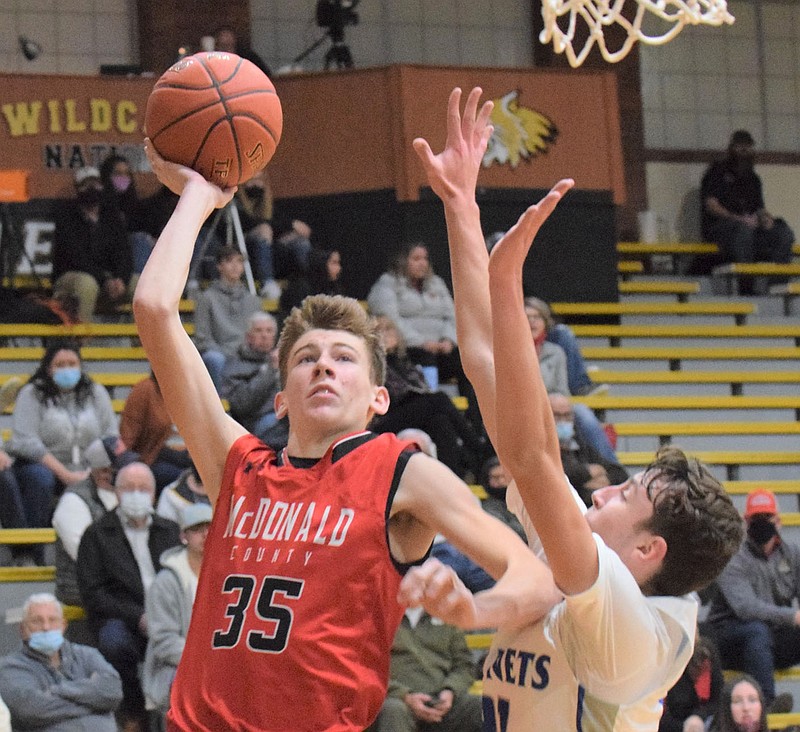 RICK PECK/SPECIAL TO MCDONALD COUNTY PRESS McDonald County's Eli McClain shoots over Cole Griesemer of Hillcrest High School during the Hornets' 71-46 win on Dec. 28 in the first round of the Neosho Holiday Classic.