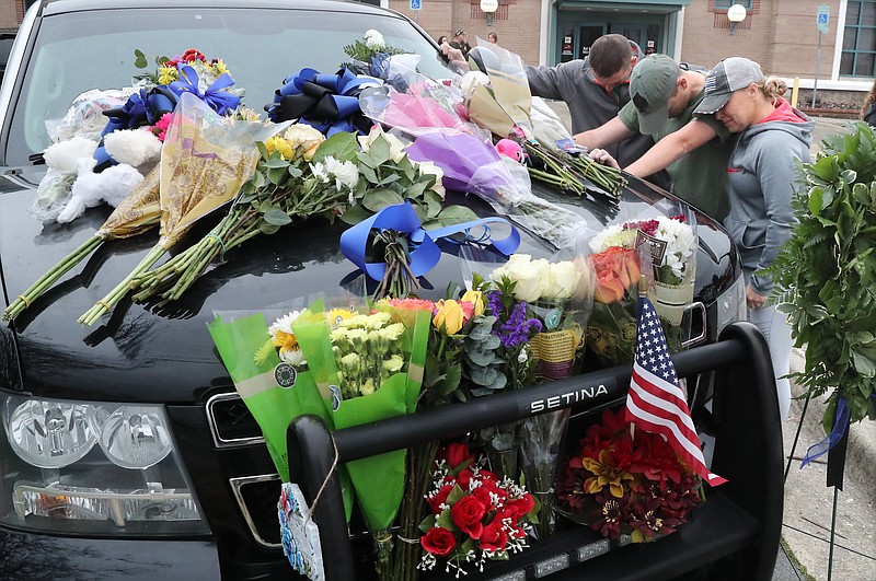 From left, Hot Springs police Officer Shawn Woodall, Officer Cody Rollins and Officer 1st Class Shannon Steed bow in a moment of prayer next to the patrol unit of Officer 1st Class Brent Scrimshire, who was shot and killed March 10 during a traffic stop. - Photo by Richard Rasmussen of The Sentinel-Record