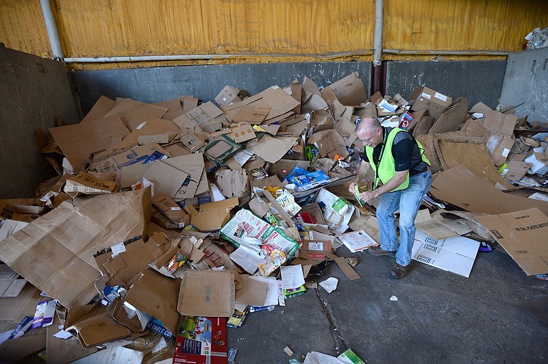Brian Pugh, Waste Reduction Coordinator for the city of Fayetteville's Recycling and Trash Collection Division, removes a contaminant Friday, June 19, 2020, from a pile of corrugated cardboard at the division's facility. Recycling collection during suspension of the curbside program was about 79% of what it was from March to June last year. The city’s curbside service resumes Monday.Visit nwaonline.com/200621Daily/ for today's photo gallery.
(NWA Democrat-Gazette/Andy Shupe) story.lead_photo.caption
