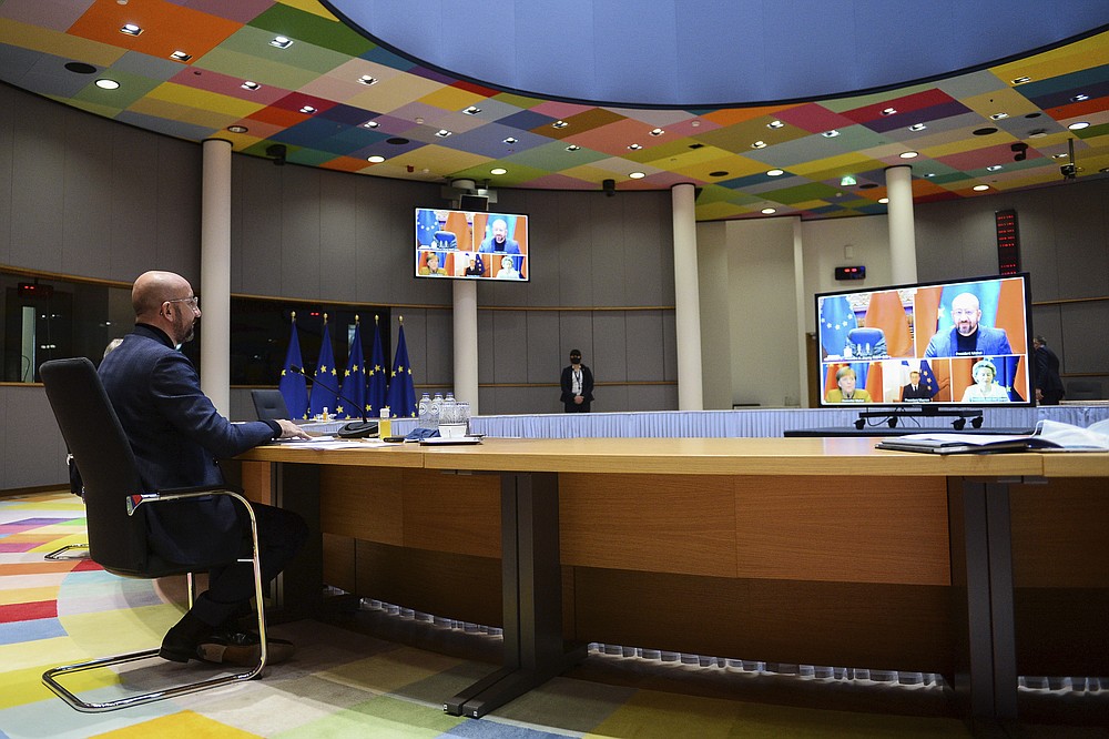 European Council President Charles Michel, left, looks at screen displaying European Commission President Ursula von der Leyen, bottom right, German Chancellor Angela Merkel, bottom left, French President Emmanuel Macron, bottom center, during an EU-China Leaders' meeting video conference at the European Council headquarters in Brussels, Wednesday, Dec. 30, 2020. The European Union top officials and China president Xi Jinping will conclude Wednesday a business investment deal that will open big opportunities to European companies, with the potential to irk the new American administration. (Johanna Geron, Pool Photo via AP)
