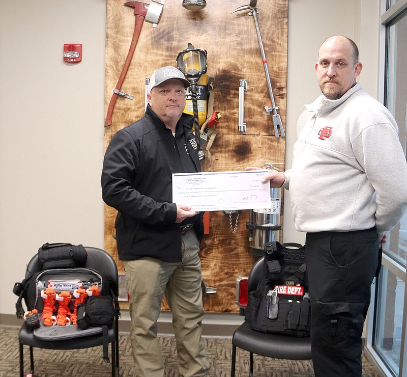 LYNN KUTTER ENTERPRISE-LEADER
Farmington Fire Chief Bill Hellard, right, accepts a $5,000 donation from Scott Murphy with Riggins Construction for active shooter response gear. Hellard said the equipment will allow Farmington firefighters to go into an active shooter situation or another emergency and begin to treat people as soon as possible. The donation was used to purchase two ballistic vests and two ballistic helmets, along with other equipment, such as bleeding control equipment and drag devices to pull people to safety. Murphy, who is a captain with Farmington Fire Department, said he suggested the donation to Riggins because the company is building two large residential subdivisions within the city limits.