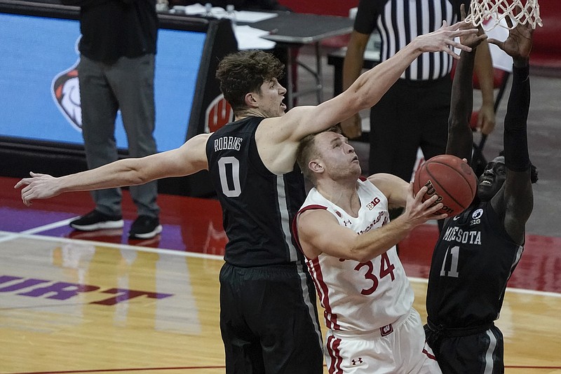 Wisconsin's Brad Davison shoots between Minnesota's Liam Robbins and Both Gach during the second half of an NCAA college basketball game Thursday, Dec. 31, 2020, in Madison, Wis. (AP Photo/Morry Gash)