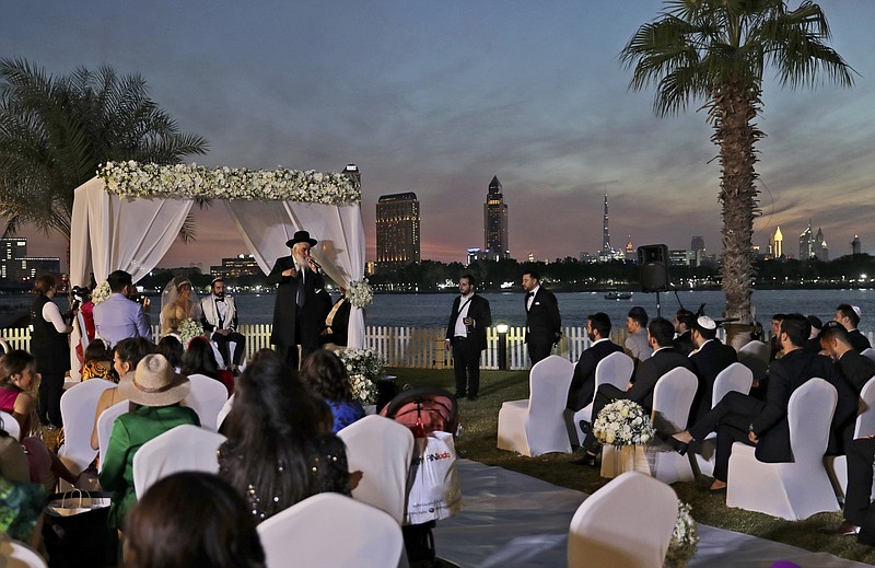 A rabbi officiates under a traditional Jewish wedding canopy during marriage ceremony of the Israeli couple Noemie Azerad, left sited under the canopy, and Simon David Benhamou, at a hotel in Dubai, United Arab Emirates, Thursday, Dec. 17, 2020.  For the past month, Israelis long accustomed to traveling incognito, if at all, to Arab countries, have made themselves at home in the UAE’s commercial hub.(AP Photo/Kamran Jebreili)