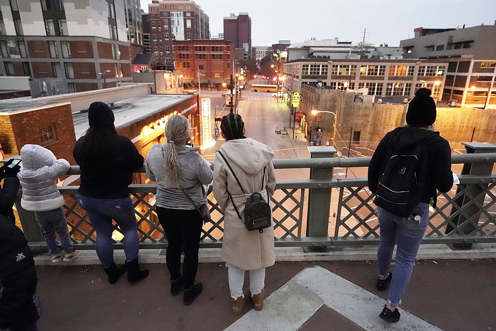 People look from a pedestrian bridge, Monday, Dec. 28, 2020, to view the area several blocks away where an explosion took place Christmas Day in Nashville, Tenn. Federal officials now turn to exploring the monumental task of piecing together the motive behind the bombing that severely damaged dozens of downtown Nashville buildings and injured three. Officials have named 63-year-old Anthony Quinn Warner as the man behind the mysterious explosion in which he was killed, but the motive has remained elusive. (AP Photo/Mark Humphrey)