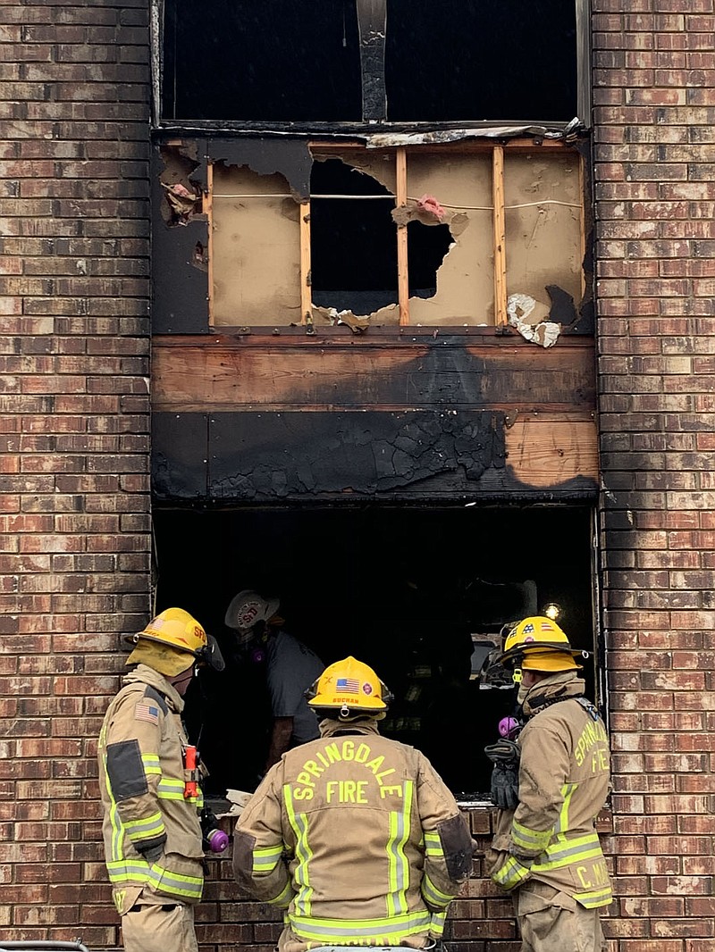 Springdale firefighters examine the scene of an apartment fire Saturday at Colony Square Apartments. (NWA Democrat-Gazette/Mary Jordan)