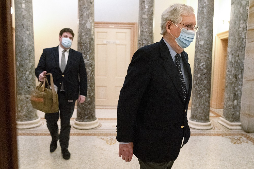 Followed by a staffer holding a bag, Senate Majority Leader Mitch McConnell of Ky., right, leaves the Capitol for the day, Tuesday, Dec. 29, 2020, on Capitol Hill in Washington. (AP Photo/Jacquelyn Martin)
