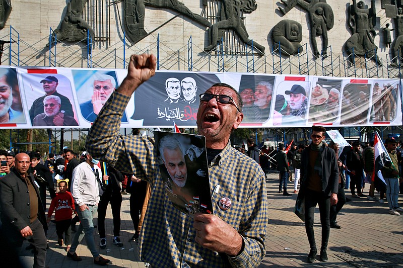A man chants slogans against the United States while supporters of Popular Mobilization Forces hold posters of Abu Mahdi al-Muhandis, deputy commander of the Popular Mobilization Forces, and General Qassem Soleimani, head of Iran's Quds force during a protest, in Tahrir Square, Iraq, Sunday, Jan. 3, 2021. Thousands of Iraqis converged on a landmark central square in Baghdad on Sunday to commemorate the anniversary of the killing of Soleimanil and al-Muhandis in a U.S. drone strike. (AP Photo/Khalid Mohammed) story.lead_photo.caption