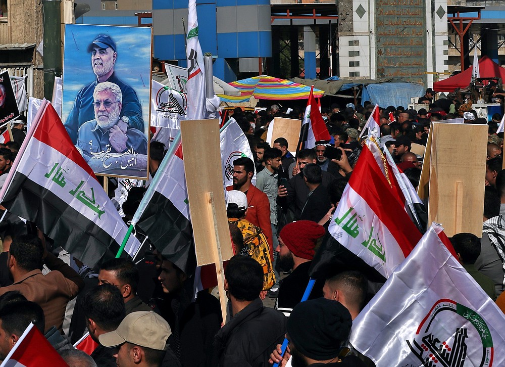 Supporters of the Popular Mobilization Forces hold a poster of Abu Mahdi al-Muhandis, deputy commander of the Popular Mobilization Forces, front, and General Qassem Soleimani, head of Iran's Quds force during a protest, in Tahrir Square, Iraq, Sunday, Jan. 3, 2021. Thousands of Iraqis converged on a landmark central square in Baghdad on Sunday to commemorate the anniversary of the killing of Soleimanil and al-Muhandis in a U.S. drone strike. (AP Photo/Khalid Moha