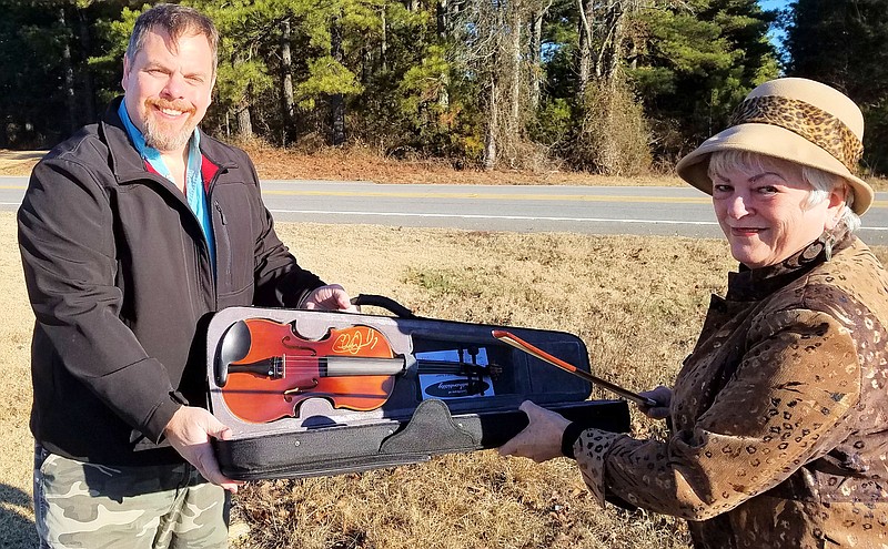 Freedom Sings Arkansas Program Director Paul W. Tull, left, delivers a Charlie Daniels autographed fiddle to Hot Springs Village resident Sheila Beatty-Krout on Christmas Eve. - Submitted photo