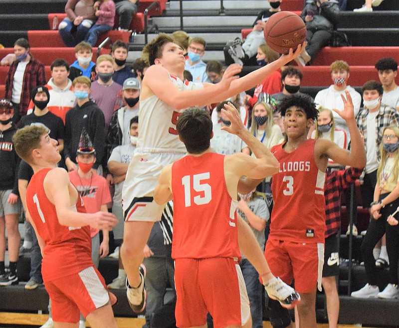 RICK PECK/SPECIAL TO MCDONALD COUNTY PRESS McDonald County's Cross Dowd splits a trio of Carl Junction defenders for a layup during the Mustangs 89-70 win on Jan. 4 at MCHS.