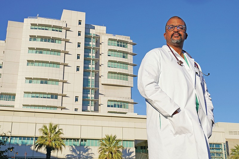 Dr. David Tom Cooke, head of general thoracic surgery at UC Davis Health, poses outside the UC Davis Medical center in Sacramento, Calif., Friday, Dec. 18, 2020. Cooke participated in Pfizer's clinical trial for the coronavirus as part of an effort to reduce skepticism about the vaccine among African Americans. He's now promoting the vaccine's safety and the importance of taking it on his social media pages. (AP Photo/Rich Pedroncelli)