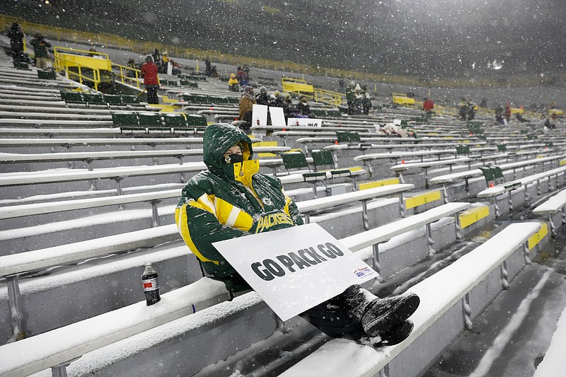 FILE - A few fans watch in Lambeau Field during the first half of an NFL football game between the Green Bay Packers and the Tennessee Titans in Green Bay, Wis., in this Sunday, Dec. 27, 2020, file photo. The eight teams hosting NFL playoff games this month are more than happy to be staying home with all of comfort it brings, but the actual advantage of playing there all but disappeared during this pandemic season of mostly empty stadiums. (AP Photo/Mike Roemer, File)