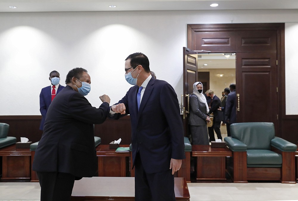 Sudanese Prime Minister Abdullah Hamdok, left, elbow bumps as he welcomes US Treasury Secretary Steven Mnuchin to the Cabinet Building, in Khartoum, Sudan, Wednesday, Jan. 6, 2021. The U.S. and Sudan have agreed to settle the African country's debt to the World Bank. The move comes after Mnuchin arrived in Sudan, the first visit by a senior American official since President Donald trump removed Sudan from the list of state sponsors of terrorism. (AP Photo)