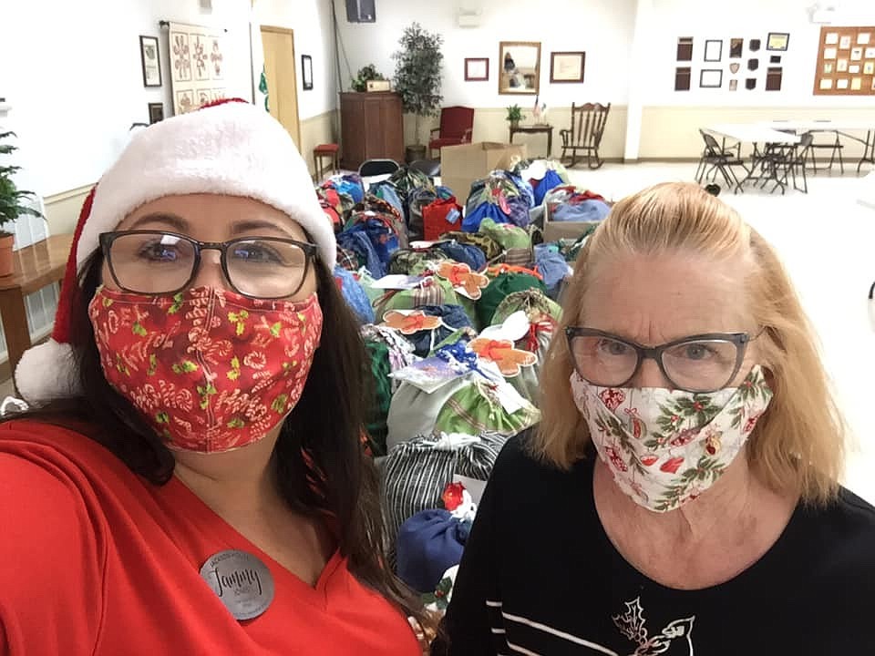 Tammy Jones with Jackson House receives 105 drawstring bags made and filled by Garland County Extension Homemakers members for tweens and teens served by the Jackson House family Christmas program from Rita Blackwood. - Submitted photo