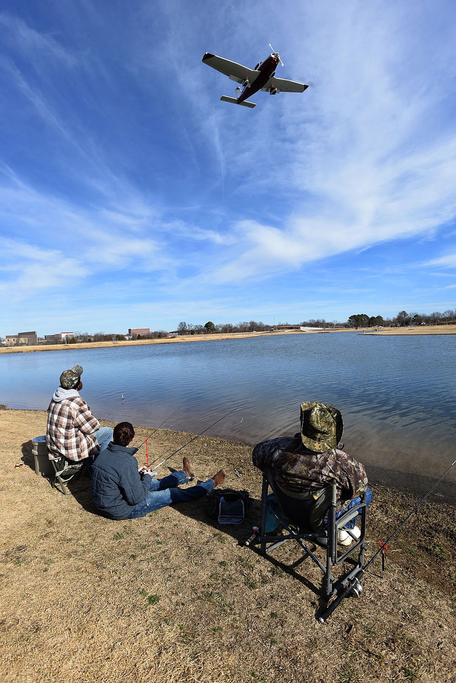 Anglers watch airplanes land while fishing for trout on Dec. 26 2020 at Lake Bentonville. The lake hugs the runway on the north side of the airport.
(NWA Democrat-Gazette/Flip Putthoff)