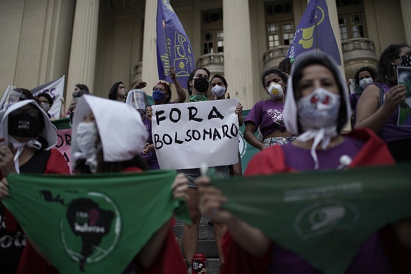 FILE - In this Sept. 28, 2020 file photo, an abortion-rights protester holds a sign that reads in Portuguese "Get out Bolsonaro" directed at Brazilian President Jair Bolsonaro during a demonstration marking the "Day for Decriminalization of Abortion in Latin America and the Caribbean," outside the state legislative assembly in Rio de Janeiro, Brazil, Monday, Sept. 28, 2020. Backed by Brazilian conservatives and evangelicals, lawmaker-turned-President Bolsonaro has said that if Congress legalized abortion, he would veto. (AP Photo/Silvia Izquierdo, File)