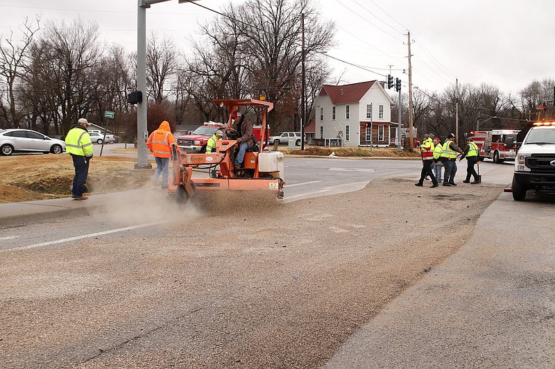 LYNN KUTTER ENTERPRISE-LEADER
Employees with Farmington's public works department work to clean up a diesel spill Thursday (Jan. 7) at the intersection of Rheas Mill Road and Main Street in Farmington. According to Lt. Chad Parrish with Farmington Police Department, a vehicle traveling south from Rheas Mill onto Main Street hit the side of s semi-truck that was west bound and ran a red light. The accident damaged the semi-truck's diesel tank. Floyd Shelley, public works manager, said it took about two hours to clean up the spill, which he estimated at 30 gallons. Gurcharan Johal with Johal Transport out of North Carolina was driving the semi-truck. No injuries were reported and no one was given a citation, Parrish said. In addition to Farmington police and public works employees, Farmington Fire Department, Fayetteville Hazmat team and the Arkansas Highway Patrol responded to the scene. Shelley said a hazmat company came and picked up the diesel from the public works department that afternoon.