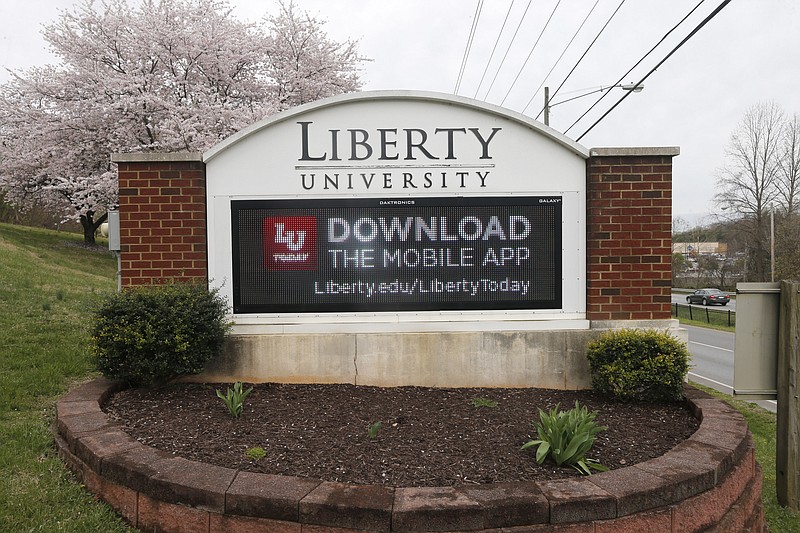 FILE-This Tuesday March 24, 2020 file photo shows s sign that marks an entrance to Liberty University as students were welcomed back to the campus during the coronavirus outbreak in Lynchburg, Va.  Liberty University sued Virginia Gov. Ralph Northam on Friday, Jan. 8, 2021 accusing his administration of wrongfully denying financial aid to some of the evangelical school's online students.  (AP Photo/Steve Helber,File)