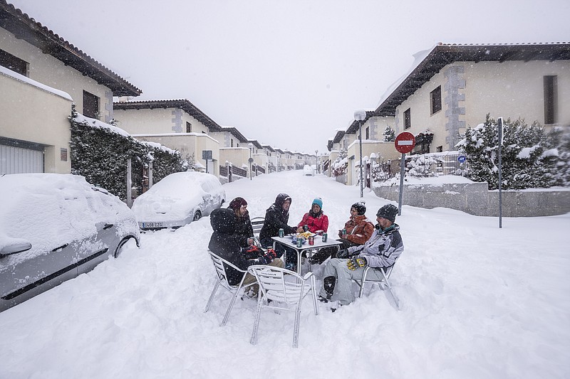 Neighbours have drinks in the middle of the street during a heavy snowfall in Bustarviejo, outskirts of Madrid, Spain, Saturday. A persistent blizzard has blanketed large parts of Spain with 50-year record levels of snow, halting traffic and leaving thousands trapped in cars or in train stations and airports that suspended all services as the snow kept falling on Saturday. Half of Spain is on alert, with five provinces on their highest level of warning. - AP Photo/Bernat Armangue