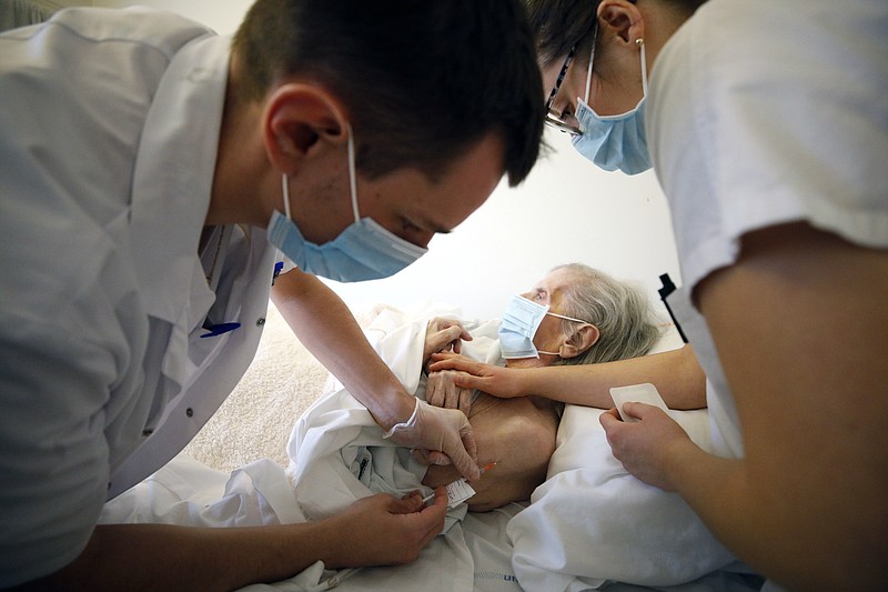 FILE - In this Jan. 6, 2021, file photo, Dr. Cedric Waechter, left, administers the Pfizer-BioNTech COVID-19 vaccine to a resident of the Bois Fleuris nursing home in Strasbourg in eastern France. As France examines why its vaccination campaign has started so slowly, the answer lies partly in the red tape and the government’s decision to start with perhaps the toughest group to reach: the elderly in nursing homes. (AP Photo/Jean-Francois Badias, File)