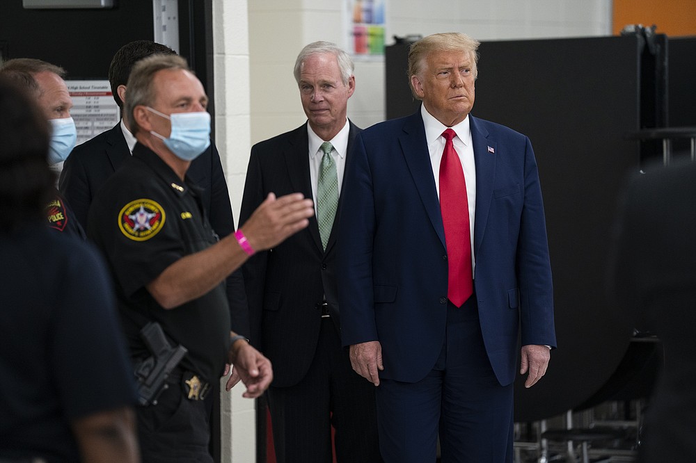 FILE - In this Sept. 1, 2020 file photo, President Donald Trump listens to Kenosha County Sheriff David Beth at the emergency operations center at Mary D. Bradford High School, in Kenosha, Wis. Background at center is U.S. Sen. Ron Johnson, R-Wis. On Thursday, Jan. 7, 2021, Johnson says he has not made a decision yet on his political future as the vocal backer of President Donald Trump faces two years in the minority and mounting calls for him to step aside. (AP Photo/Evan Vucci File)